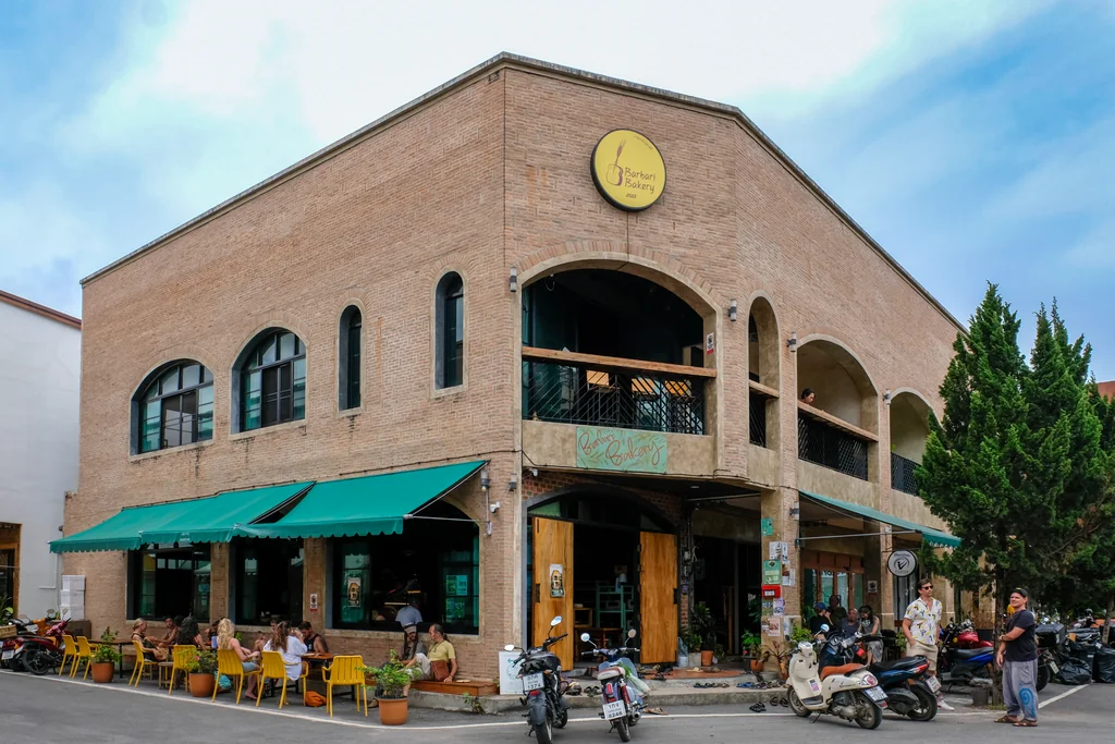 Barbari Bakery brick building with green awning and yellow chairs